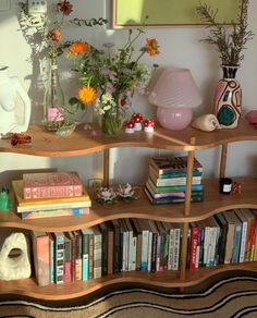 a bookshelf filled with lots of books next to a vase full of flowers