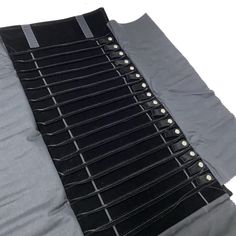 several pieces of black and grey fabric with metal buttons on the bottom one is folded down