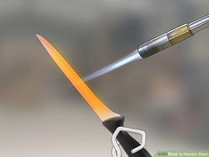 a pair of scissors cutting through the tip of a pen with a lighter in it