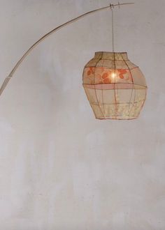 a lamp hanging from a ceiling next to a white wall with an orange and red design on it