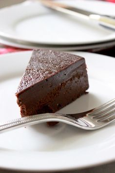 a piece of chocolate cake sitting on top of a white plate next to a fork