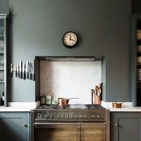 a kitchen with a clock on the wall next to a stove top oven and cabinets