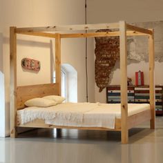 a bed frame made out of wood and white linens