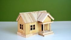 a small wooden house sitting on top of a white table next to a green wall