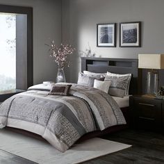 a large bed in a bedroom with gray walls and wooden flooring next to a window