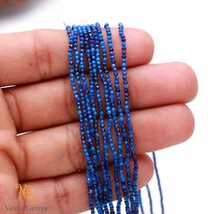 a hand holding some blue beads in it's left hand and another beaded bracelet on the right