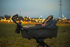 a baby stroller sitting in the grass at night with its handle extended to it's side