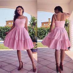 a woman in a pink dress standing on a patio with her back to the camera