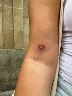 a woman's arm with a small sun tattoo on the left side of her arm