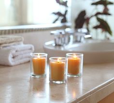 three candles sitting on top of a bathroom counter