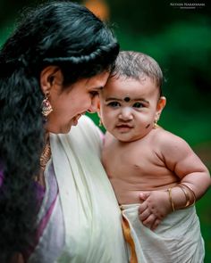 a woman holding a baby in her arms and wearing a sari on it's chest