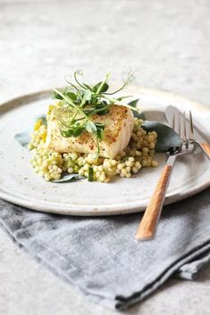 a white plate topped with food next to a fork and knife on top of a table