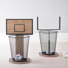 two trash cans sitting next to each other on top of a wooden table with a basket in the middle