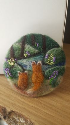 a needle - felted brooch with an image of a fox and her cub