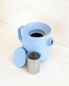 a blue coffee pot with a cup in it