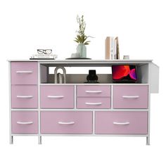 a white and pink dresser with many drawers on it's sides, including a plant