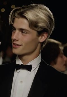 a young man in a tuxedo and bow tie looking at something off to the side