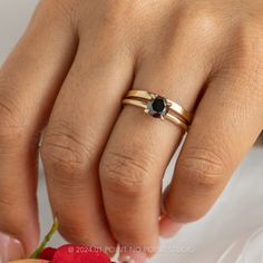 a close up of a person's hand with a ring on their finger and an apple in the background