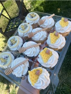 cupcakes with white frosting and honey combs on top are sitting in a plastic container