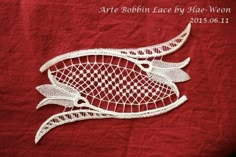 a red table cloth with an embroidered fish design on the front and bottom, in white thread