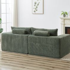 a green couch sitting on top of a hard wood floor next to a fire place