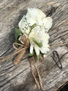 a bouquet of white flowers tied to a piece of wood with some hair pins on it