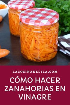 two jars filled with carrots sitting on top of a table next to other vegetables