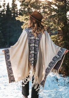 a woman walking in the snow wearing a shawl