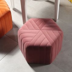 a pink ottoman sitting on top of a white floor next to two orange stools