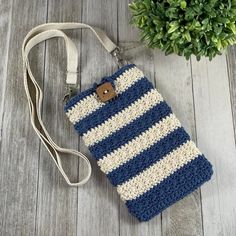 a blue and white crocheted cell phone case sitting on top of a wooden floor