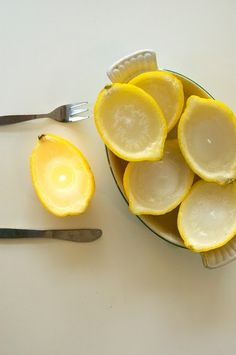 a bowl filled with sliced lemons next to a knife and fork on top of a table