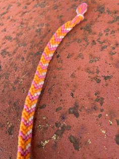 an orange, pink and yellow rope on top of a red surface with small holes in it