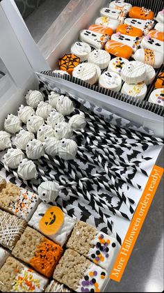 an assortment of decorated cookies and pastries on display in a bakery case with halloween decorations