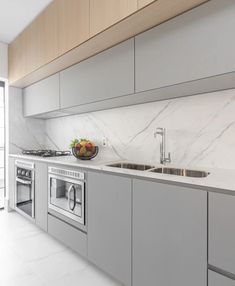 a modern kitchen with marble counter tops and stainless steel appliances, along with large windows