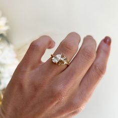 a woman's hand with a ring on it and a flower in the background