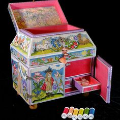 an elaborately painted jewelry box with drawers and thread spools on the floor