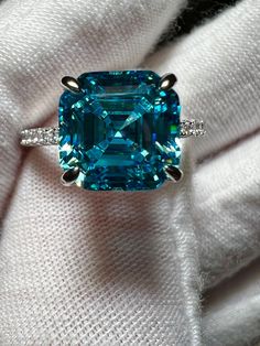 3CT Asscher Cut Cyan Created Blue Tourmaline 925 Sterling Silver Platinum Ring Size 7.  A gorgeous hidden halo add to this glorious ring.  Accents are grade 5A zirconia for sparkle! Stunning sparkle and color!   Blue tourmaline is the general term applied to two rare varieties of tourmaline: Paraiba tourmaline and indicolite tourmaline. Pure blue tourmaline is exceptionally rare, since most blue tourmaline exhibits a noticeable secondary green hue. Gia Certified Aquamarine Jewelry Ring, Blue Emerald Ring With Halo Setting, Blue Emerald Halo Setting Ring, Gia Certified Aquamarine Ring, Blue Emerald Rings With Halo Setting, Blue Emerald-cut Moissanite Jewelry, Blue Moissanite Jewelry With Halo Setting, Gia Certified Blue Topaz Ring, Blue Emerald Jewelry With Accent Stones