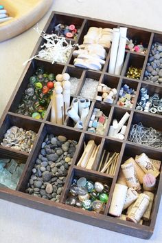 a wooden box filled with lots of different types of beads and other items on top of a table