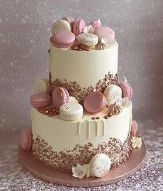 a three tiered cake decorated with macaroons and other desserts on a table