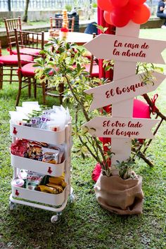 a sign that is sitting in the grass near some chairs and tables with red balloons