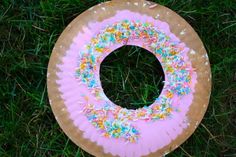 a pink frosted donut with sprinkles on it sitting in the grass