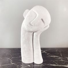 a white sculpture on top of a marble counter next to a black and white wall