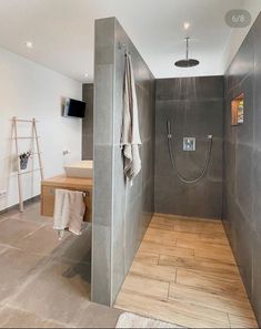 a walk in shower sitting next to a wooden table and sink on top of a hard wood floor