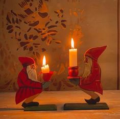 two small red gnomes holding candles in their hands