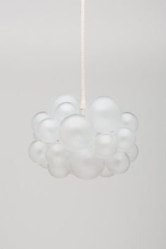 a white chandelier hanging from a ceiling with many balloons attached to the chain