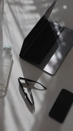 an open laptop computer sitting on top of a table next to a pair of glasses