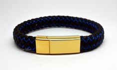 This stylish keepsake bracelet is made from 24k gold plated 316L non-tarnish stainless steel, with intricately braided black and blue leather straps.  As with all of our cremation/keepsake jewellery, it includes a discreet chamber in which to hold a small, token amount of ashes, fur, sacred earth or whatever you wish to hold close. All orders come complete with a presentation/gift box and a filling kit. The bracelet comes in 4 lengths:  Extra Small - 18cm/7.25inch long, to fit wrists up to 16cm Gold Wristband Gift, Adjustable Gold Leather Bracelet Gift, Elegant Blue Leather Bracelet For Gift, Adjustable Bracelet With Gold Clasp For Gifts, Adjustable Gold Leather Bracelet Engraved, Gold Leather Jubilee Bracelet, Handmade Gold Bracelet Wristband, Gold Engraved Leather Bracelet Gift, Handmade Gold Bangle Wristband