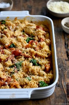 a casserole dish with pasta and spinach in it on a wooden table