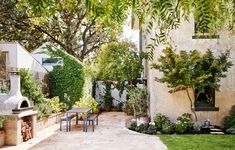 an outdoor patio area with tables, chairs and trees in the back yard on a sunny day