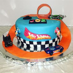 a birthday cake with cars on it and an orange ribbon around the top that says hot wheels